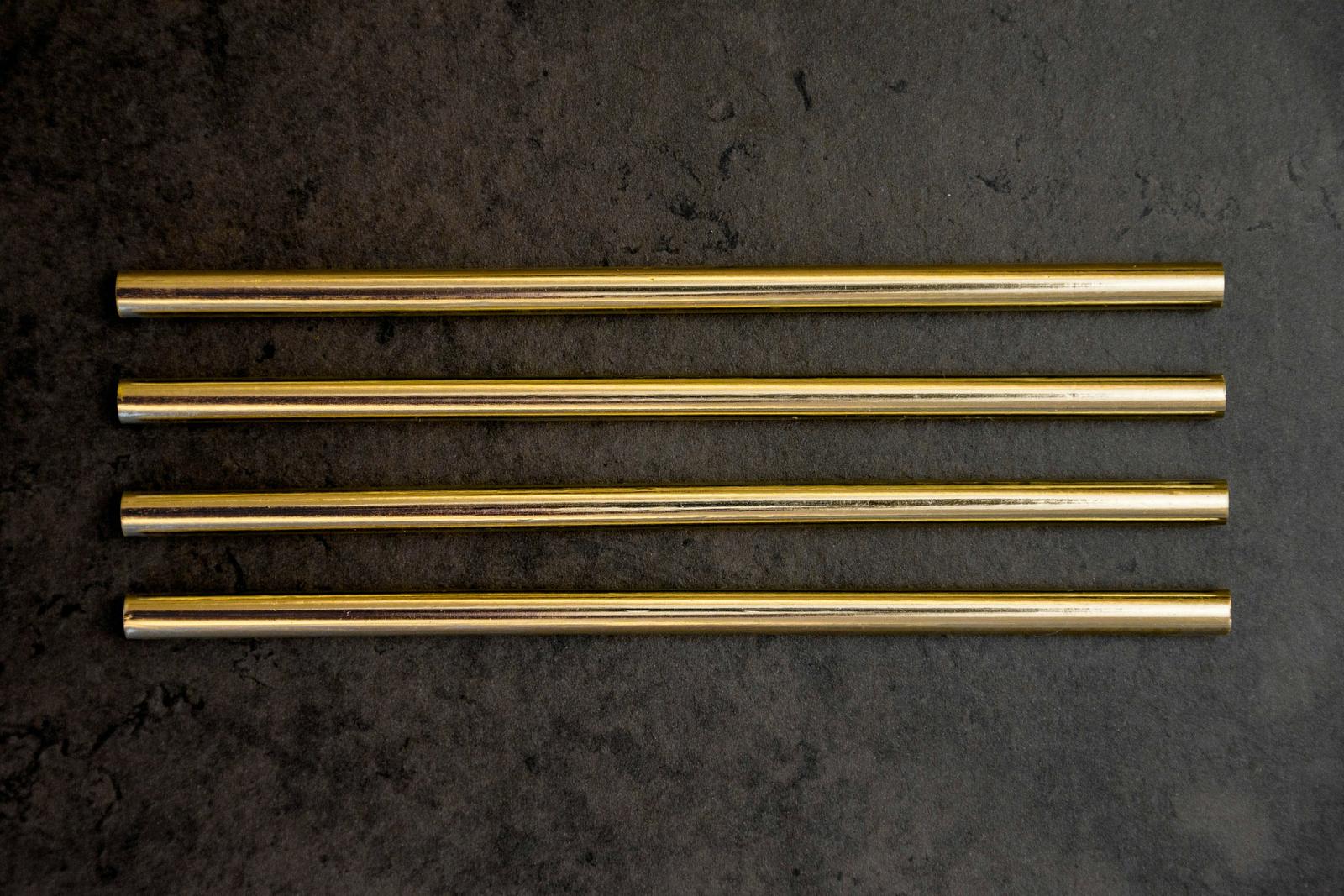 Polished copper tubes laid side by side on dark slate
