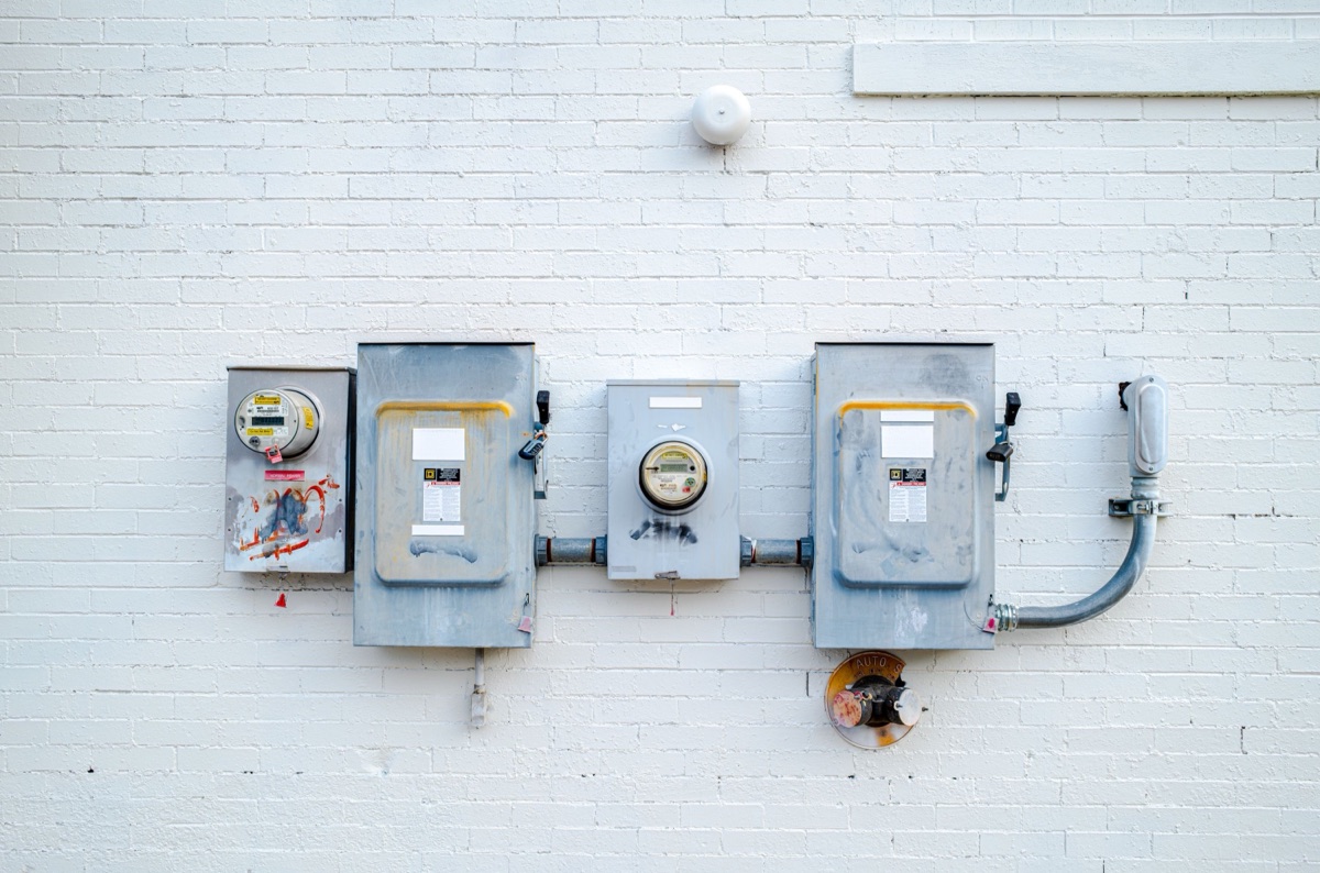 AC disconnect boxes and an electrical whip on a white brick wall