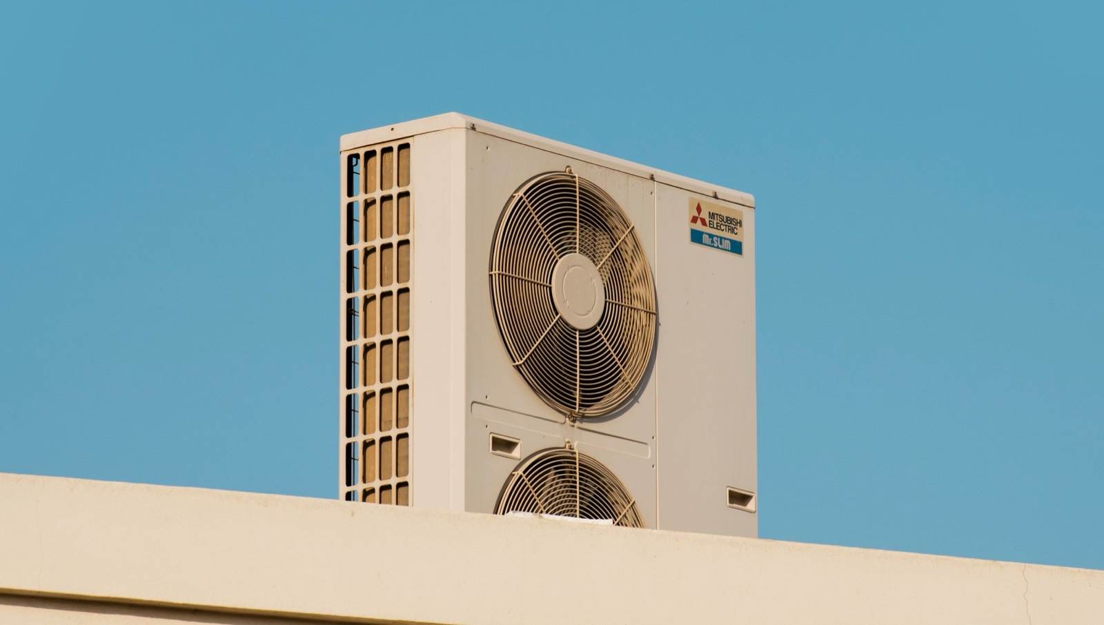 Mitsubishi Electric Mr. Slim outdoor condenser unit on a rooftop against a clear blue sky